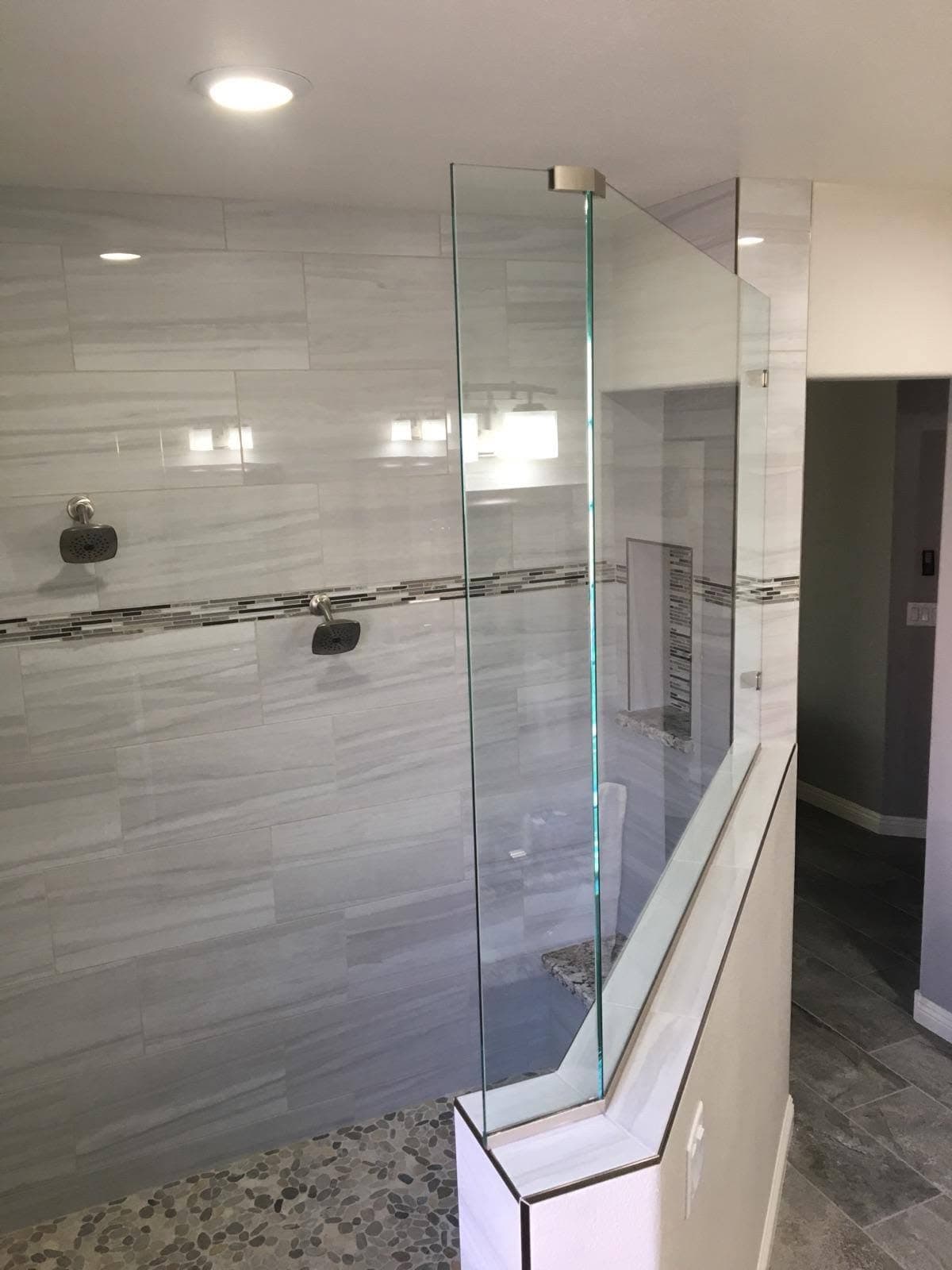 Clear glass walk-in shower enclosure on a half wall in a Las Vegas bathroom