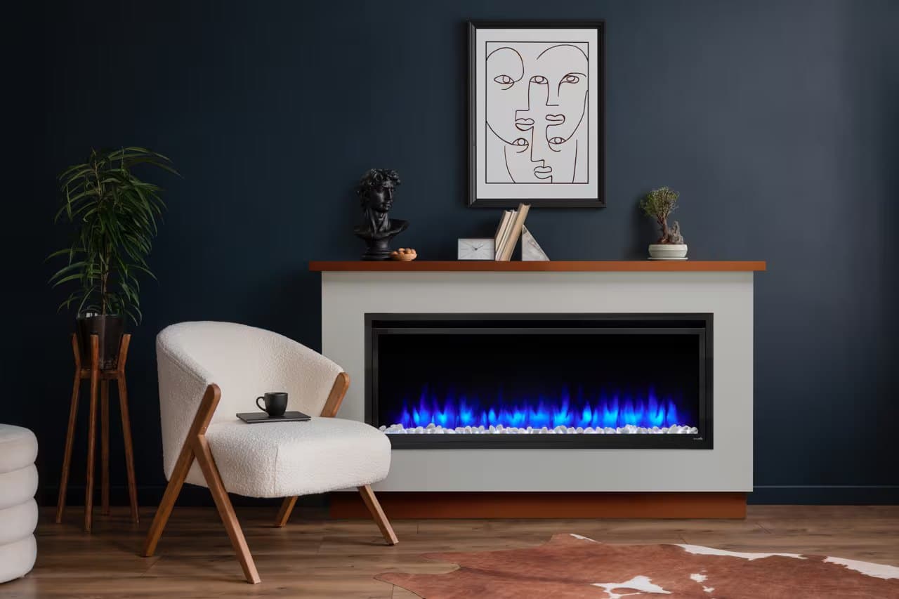 A SimpliFire linear electric fireplace with color-changing blue LED flames and a river-rock bed, set into a freestanding mantel console beside a navy accent wall