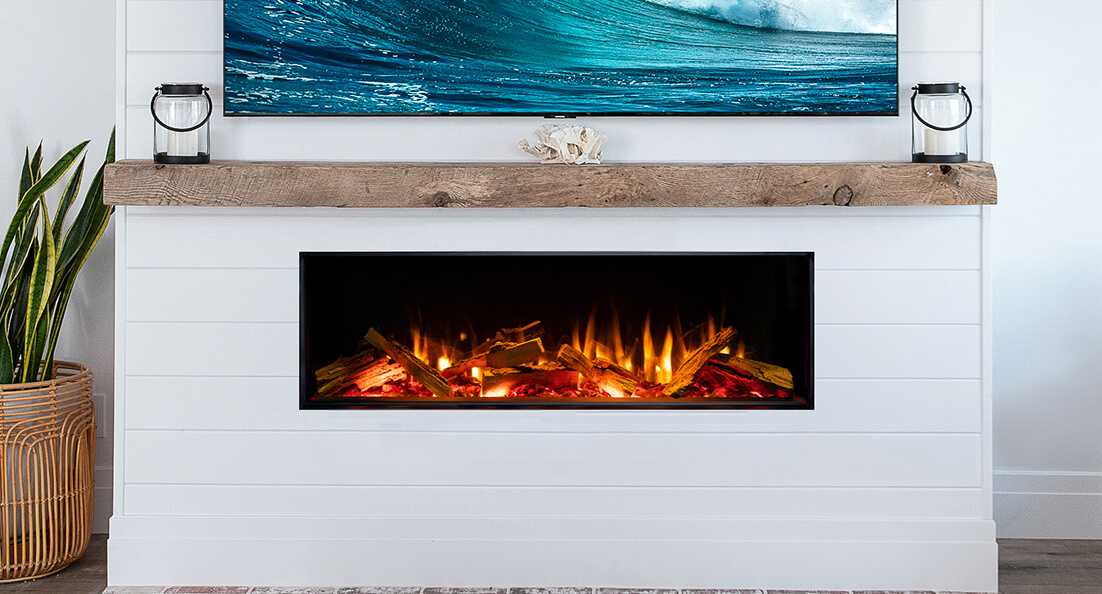 A Valor linear electric fireplace with a realistic log-set flame, set into a white shiplap wall with a wood mantel and a mounted TV above