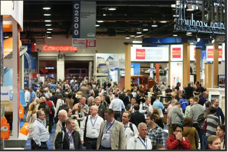 Busy convention or trade show with many people walking between booths and displays.