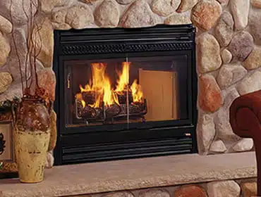 Rustic stone fireplace with a black frame and a warm, glowing fire.