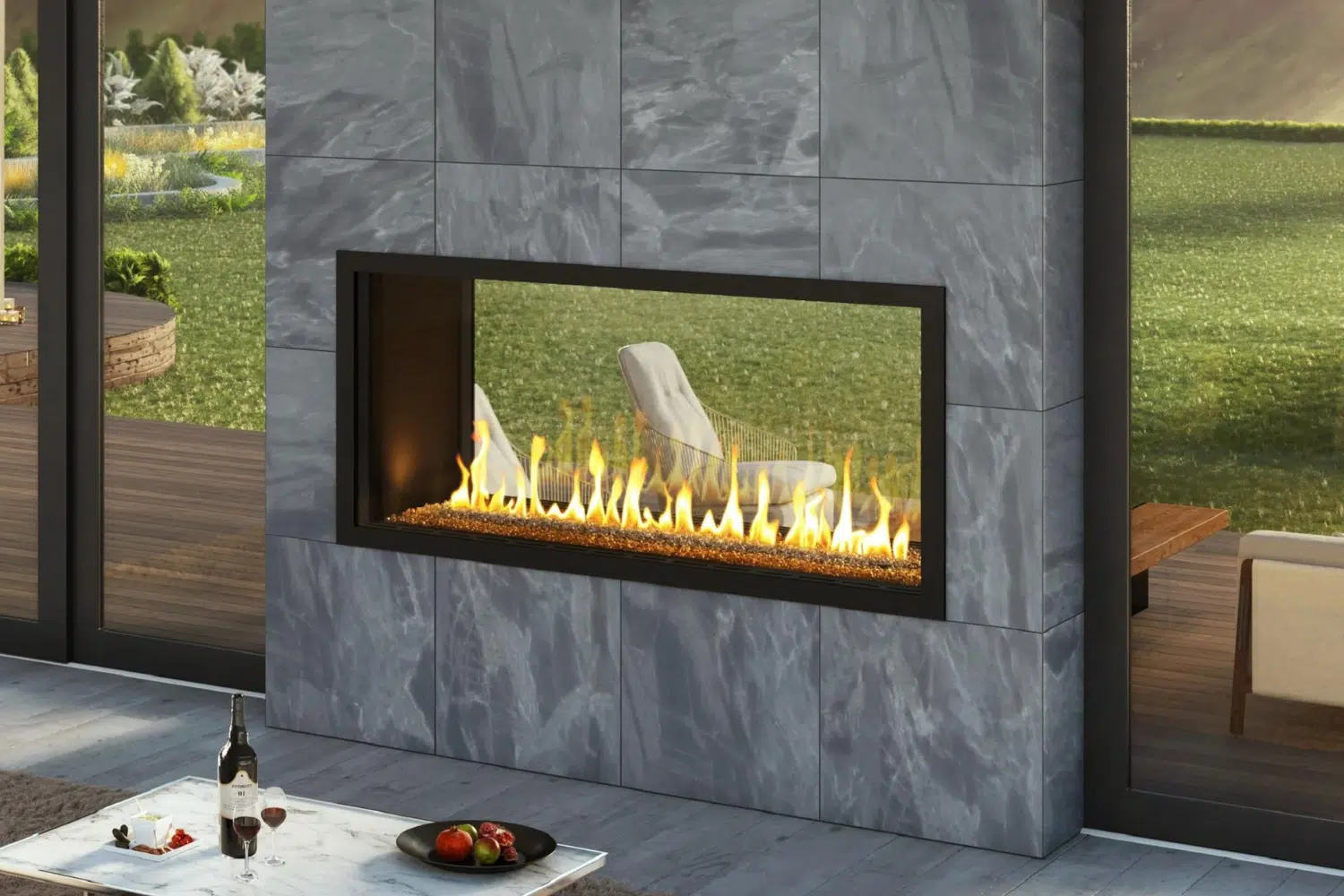 A modern indoor fireplace from Hearth & Home Specialties boasts a sleek design, set in a stone wall with vibrant flames. A table holds wine, glasses, and fruit. Large windows offer a scenic Las Vegas view of greenery and hills.