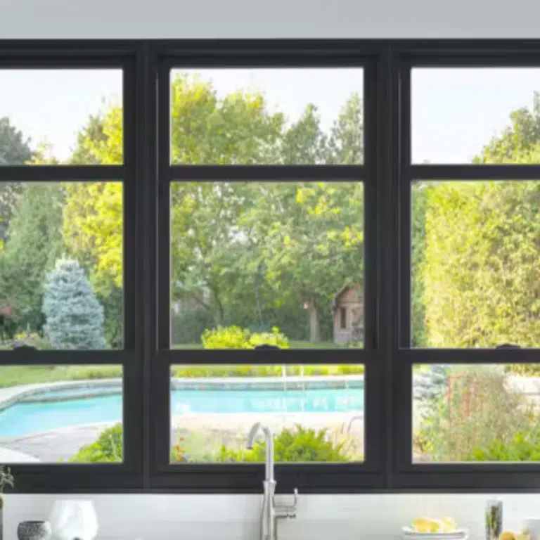 Black-framed window with a view of a garden and pool.