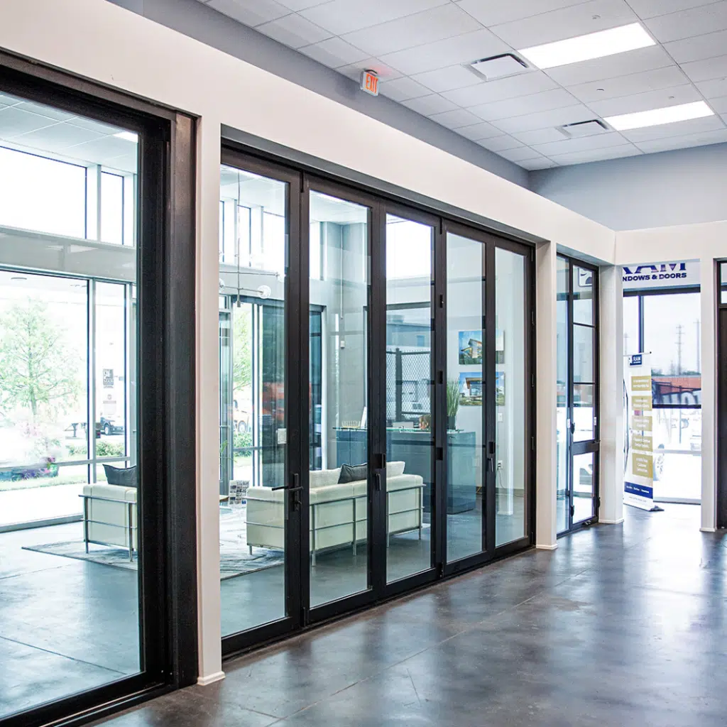 A modern showroom with custom glass sliding doors in Las Vegas. Bright natural light illuminates the interior, showcasing minimalistic white sofas and a sleek, contemporary design. Indoor and outdoor spaces blend seamlessly through transparent partitions by Hearth & Home Specialties.
