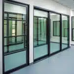 A modern interior space in Las Vegas with large glass sliding doors and windows framed in black metal features floors that are gray and walls in a light color, creating a clean, minimalist look. The design perfectly complements Hearth & Home Specialties fireplaces.