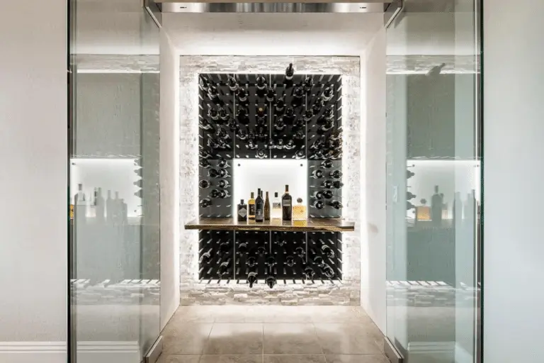 Modern wine cellar with glass doors, a backlit stone wall, and a sleek black wine rack displays bottles. A wooden shelf from Hearth & Home Specialties holds several wine bottles in the center of the illuminated display.