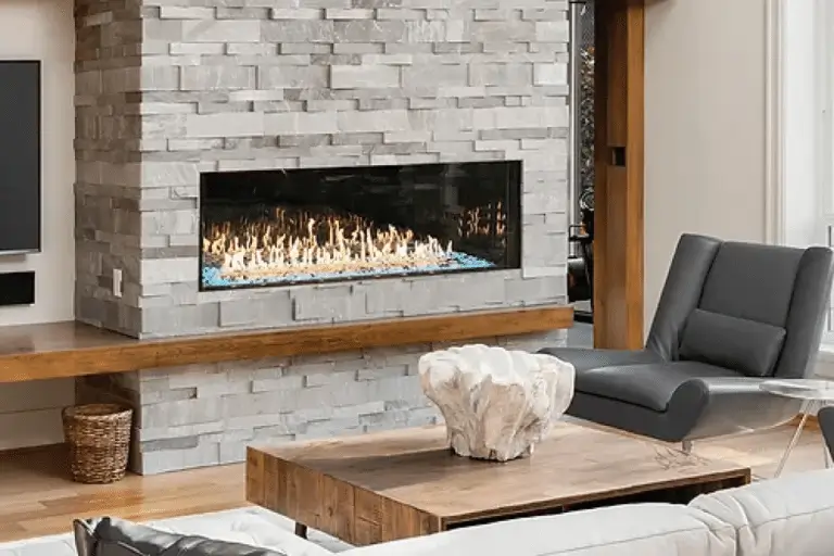 A modern living room by Hearth & Home Specialties features a sleek gray stone fireplace, a black and gray armchair, a wooden coffee table with a white decorative sculpture, and a light-colored sofa.